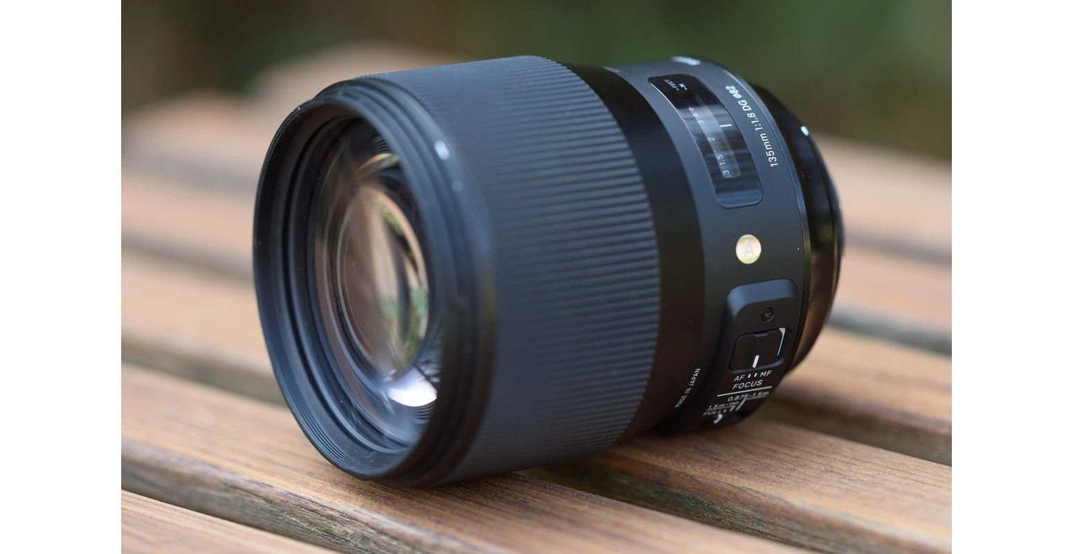 Об'єктив Sigma 135mm f/1.8 DG HSM Art на дерев'яному столі з панеллю перемикачів лімітера